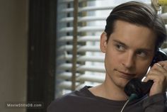 a man is talking on the phone in front of blinds