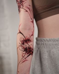 a woman's arm with red flowers on it and a black ink tattoo design