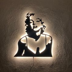 a light that is on the wall with a woman's face and birds flying around it