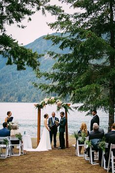 a couple getting married at the end of their wedding ceremony in front of a lake