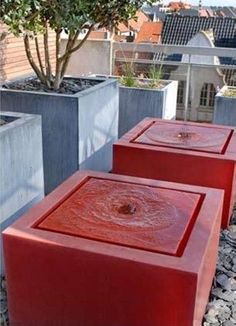 three cement planters sitting next to each other in front of a tree and buildings