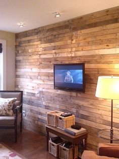 a living room with wood paneling and a flat screen tv mounted on the wall