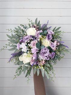 a bouquet of purple and white flowers in a vase with greenery on the side