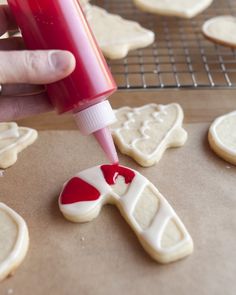 someone is making cookies with red and white icing