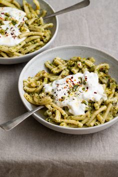 two bowls filled with pasta and sauce on top of a table