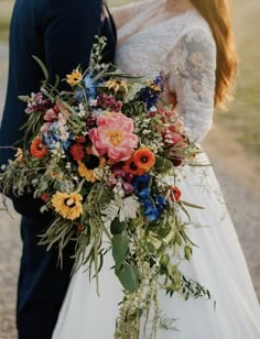 a bride and groom standing next to each other in front of a field with flowers