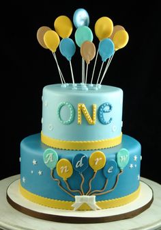 a birthday cake with balloons on top and the number one on it's side