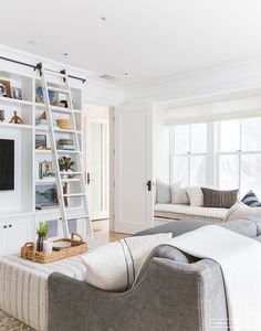 a living room with white walls and shelves filled with furniture, including a ladder to the ceiling