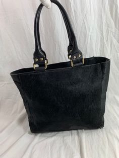 "Measurements are 14\" top wide, 10\"5 high, 5\"8 deep with two 48\" straps each side to side with a 8\" drop. On the interior there is one main compartment, unlined leather, back zipper pocket and a top magnetic closure. Bag is made of calf hair with black leather trim, gold tone hardware and chunky handles. Please note bag is not new and there are scuffs with some balding and bag is great for daily use and will last you for years to come. I WANT TO STRESS THAT THIS ITEM IS VINTAGE WHICH MEANS Rectangular Calf Hair Bag With Leather Handles, Black Calf Hair Bags For Everyday Use, Black Calf Hair Bag For Everyday Use, Chic Calf Hair Shoulder Bag For Everyday Use, Everyday Black Calf Hair Bag, Calf Hair Tote Shoulder Bag With Leather Handles, Calf Hair Tote With Leather Handles, Medium Leather Shoulder Bag For Errands, Calf Hair Tote Shoulder Bag For Travel