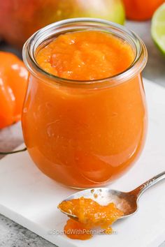 a spoon is sitting next to a jar of orange sauce