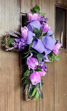 purple flowers and greenery are placed on the front door to create a cross decoration