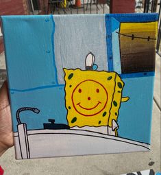 a person holding up a piece of art that looks like spongebob