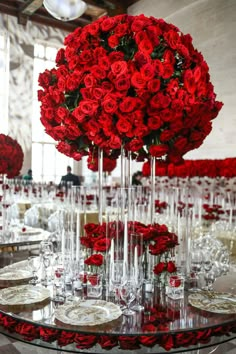 red roses are arranged in tall vases at the center of a long table set for an event