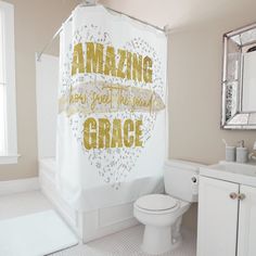 a bathroom with a shower curtain that says amazing grace in gold letters on it, next to a toilet and sink