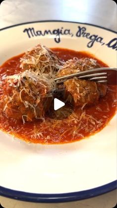 a white plate topped with meatballs covered in sauce and grated parmesan cheese