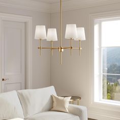 a living room scene with focus on the couch and lamps hanging from the chandelier