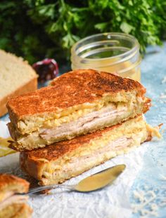 a sandwich cut in half sitting on top of a piece of paper next to a jar of jam