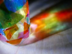 a colorful glass object sitting on top of a wooden table next to a blurry background