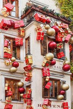 a building decorated with red and gold christmas presents hanging from it's windows in the city