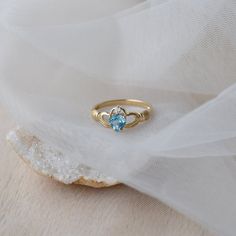 Delicate and symbolic Claddagh ring is made out of 14k solid gold and set with blue heart topaz and diamond It would make a perfect choice for the engagement or as a push gift. Ring can be made in white, rose or yellow 14k gold. Highly polished. If you want to customise this product or set it with another stones - please write to us. ❤ Hand Made with love in our studio in Prague ❤ Stone details Topaz Shape: Heart Dimensions: 5.7 mm Color: Blue Origin: Natural Diamond Amount: 1 Shape: Round Color 14k Gold Heart Ring With Birthstone For Promise, Topaz Birthstone Promise Ring Fine Jewelry, Topaz Birthstone Promise Ring In Fine Jewelry Style, Fine Jewelry Topaz Birthstone Promise Ring, Dainty Topaz Ring With Birthstone, 14k Gold Heart Cut Birthstone Ring, 14k Gold Heart Cut Birthstone Promise Ring, Dainty Topaz Birthstone Ring For Promise, Fine Topaz Birthstone Promise Ring