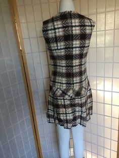 "1970's brown and white plaid drop waist mini dress with chain detail at the waist women's XS Bust 34\" Waist 30\" Hips 40\" Shoulder to hem 33 1/2\"" Fitted Plaid Vintage Mini Dress, Fitted Vintage Plaid Mini Dress, Fitted Sleeveless Plaid Vintage Dress, Fitted Sleeveless Vintage Plaid Dress, Fitted Brown Plaid Dress, Brown Fitted Plaid Dress, Fitted Brown Plaid Dress For Fall, Vintage Fitted Brown Mini Dress, Brown Fitted Vintage Mini Dress