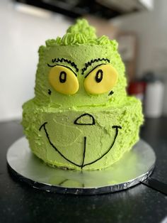 a cake with green frosting and an angry grin face on the top is sitting on a plate