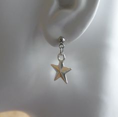 "Dull silver tone double sided star charm earrings. Small star charms dangling from stainless steel ball earring studs. Earring length: 25mm; 1\" (including the ball of the stud) Earring stud material: stainless steel Charm material: Zinc alloy, Nickel safe, Lead free This listing is for one pair of star earrings with rubber backs. This earring will come in a gift bag. I offer combined shipping costs which give you a shipping discount for ordering multiple items from my shop. Earrings care: Take Silver Star Charm Earrings In Stainless Steel, Silver Stainless Steel Star Charm Earrings, Silver Stainless Steel Earrings With Star Charm, Sterling Silver Star Earrings With Dangling Charms, Dangle Earrings Silver, Ball Stud Earrings, Earring Stud, Dope Jewelry, Earring Studs