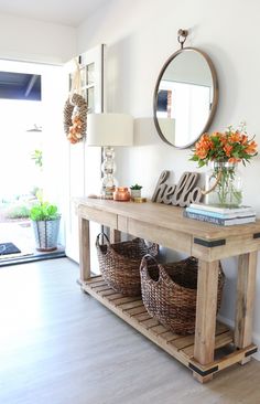 a wooden table with baskets on it and a mirror hanging above the table that says hello