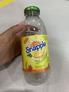 a hand holding a bottle of snapple lemonade on top of a white counter