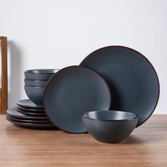 a stack of black plates on top of a wooden table