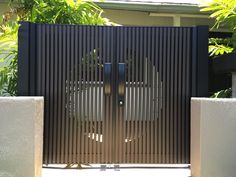 an iron gate with two faces on it and trees in the back ground behind it