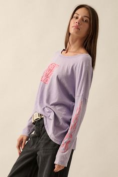 Mineral washed graphic t-shirt. Vintage-style "But She's Hot" text print with flame graphics. Long sleeves with flame print. Dropped shoulder. Round neckline. Center-back seam. Oversized fit. 100% Cotton. Imported top designed and printed in LA. Model wears size S. Oversized Long Sleeve Lavender Top, Purple Graphic Print Top For Streetwear, Purple Grunge Top With Screen Print, Grunge Purple Top With Screen Print, Urban Style Screen Print Tops For Spring, Lavender Top For Spring Streetwear, Purple Grunge Screen Printed Top, Acid Wash Long Sleeve T-shirt With Letter Print, 90s Purple Top With Graphic Print