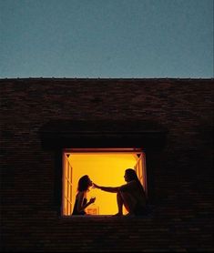 two women are sitting on a roof and one is holding her hand out to the other