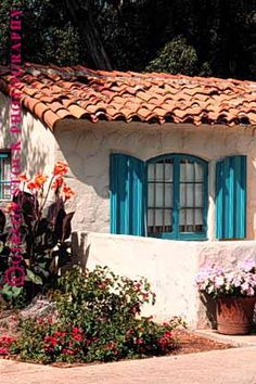 a white house with blue shutters and flowers