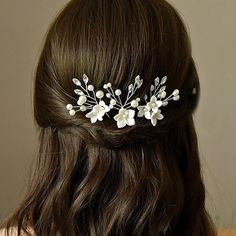 a woman with long brown hair wearing a white flower and leaf bridal headpiece