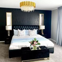 a bedroom with a large bed and chandelier hanging from the ceiling above it