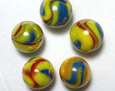 four glass marbles with multicolored swirl designs on them sitting on a white surface