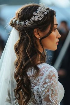 a woman in a wedding dress wearing a veil and tiara with flowers on her head