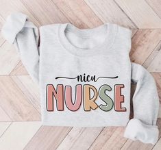 a sweater with the words nica nurse on it sitting on top of a wooden floor