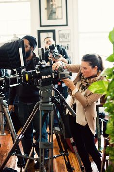 a woman standing in front of a camera on top of a wooden floor next to other people