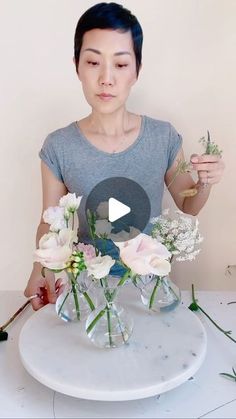 a woman is arranging flowers in vases on a table with the video below her