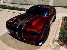 a red and black car parked on the side of a road next to a parking lot