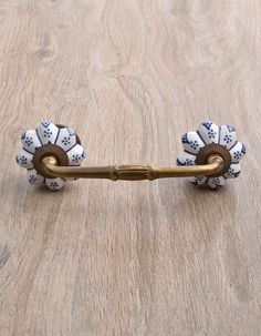 an antique brass handle with blue and white ceramic flowers on the end, sitting on a wooden surface