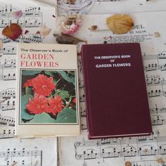 the observer's book of garden flowers sits on top of sheet music with red flowers