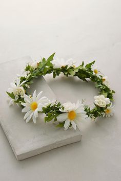 white flowers and greenery are arranged on a marble slab, with green leaves in the middle