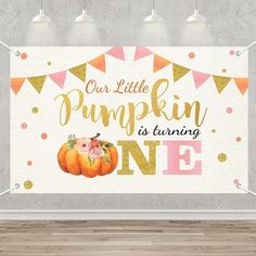 a white wall with a sign that says our little pumpkin is turning one