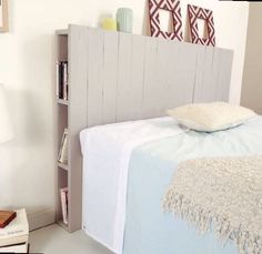 a bed with a book shelf next to it and a pillow on top of it