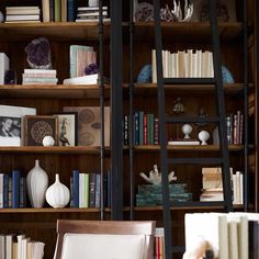 a book shelf filled with lots of books next to a vase and other items on top of a wooden table