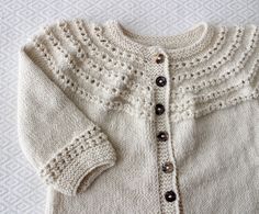 a white knitted sweater with buttons on it