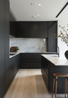 a kitchen with black cabinets and white marble counter tops